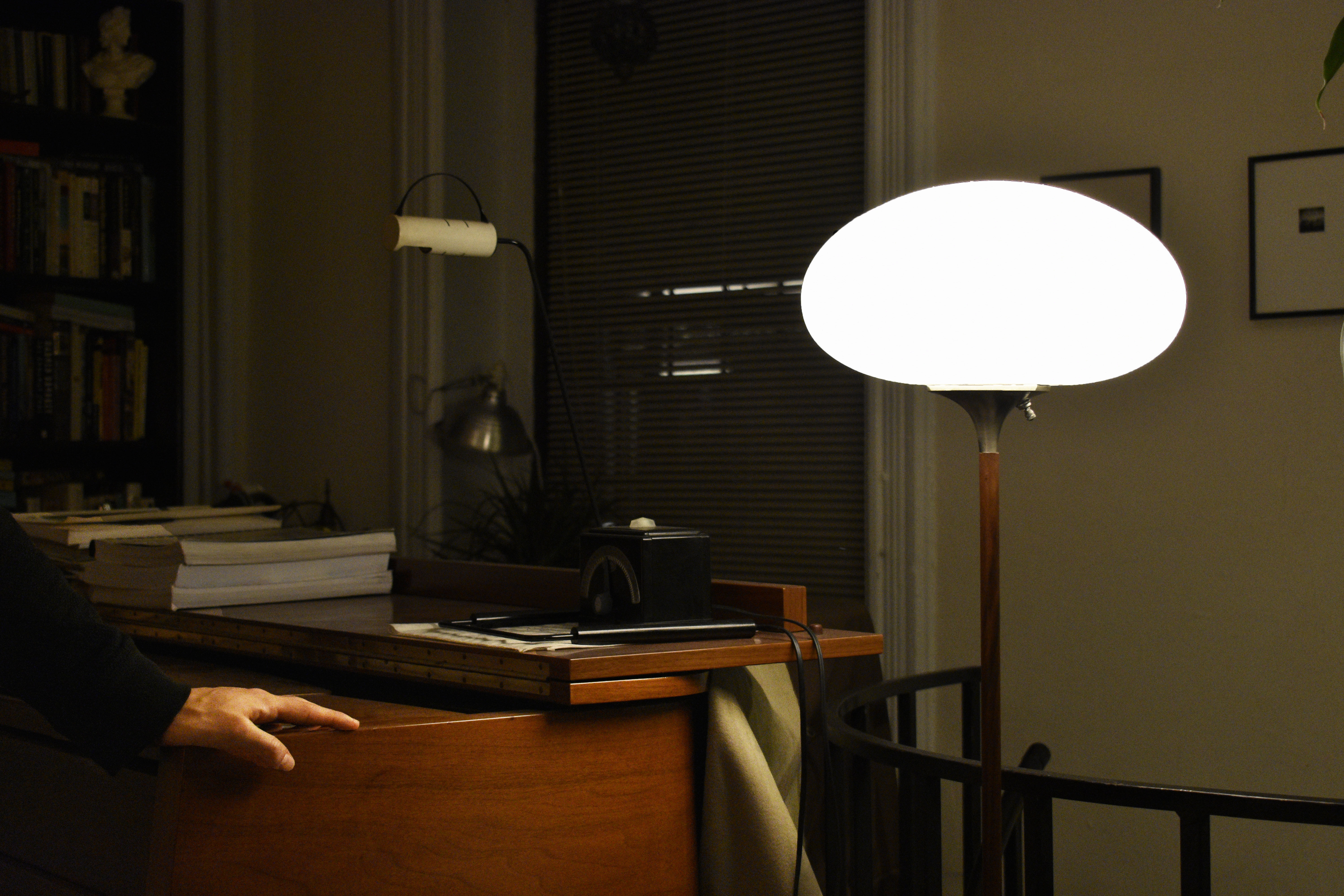 Ben leaning on the piano in his apartment, with a large, bright lamp right of frame.